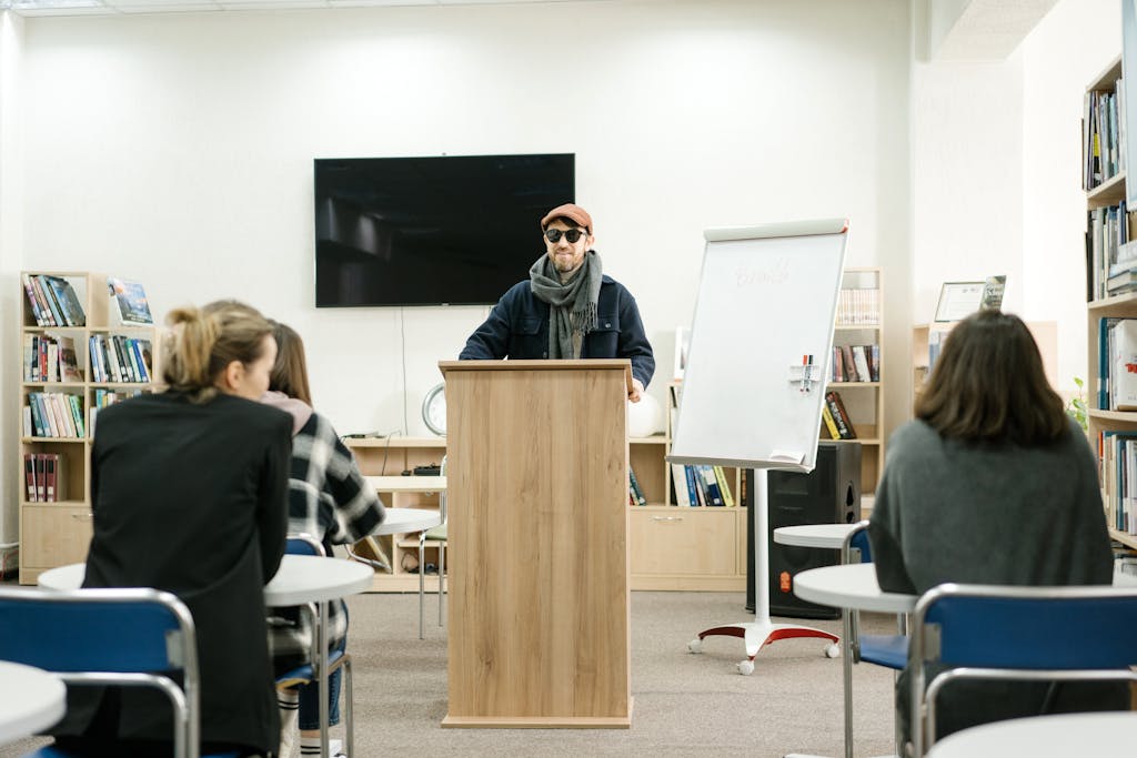 Person with visual impairment speaking at a lectern during a professional presentation or workshop.