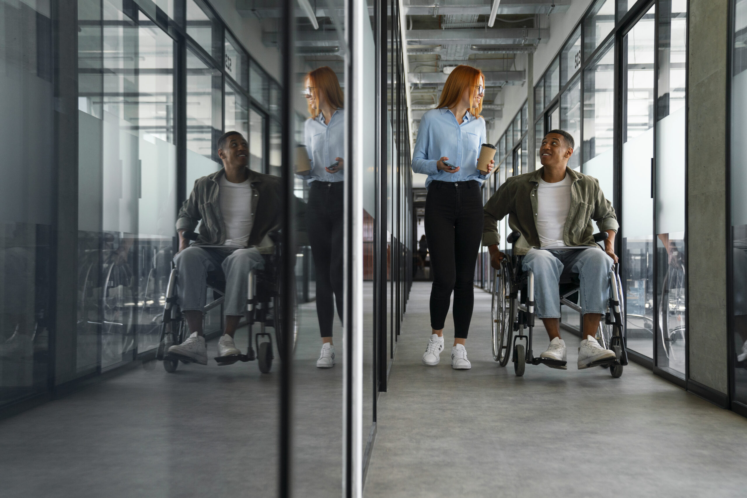 Wheelchair user and colleague moving through a modern accessible office environment.