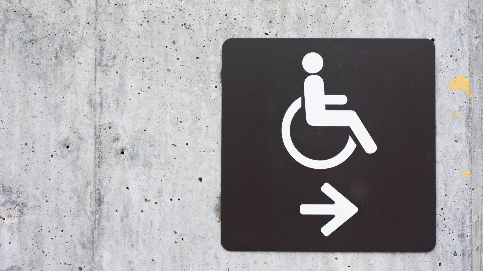 Accessible route sign displaying a wheelchair symbol and directional arrow.